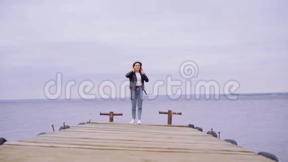 一个穿黑色皮夹克的女孩正走在河上的一座木桥上美丽的自由时刻与和平视频的预览图