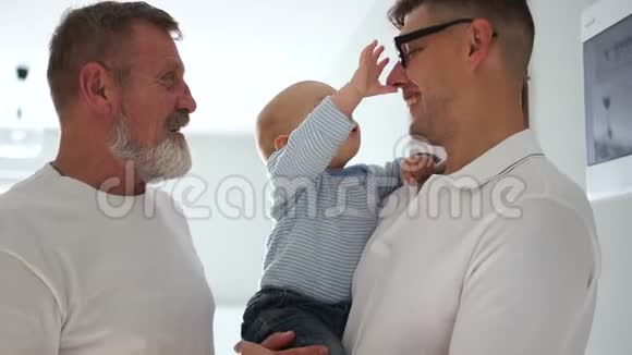 祖父儿子和孙子在家一个孩子把祖父眼镜戴在他父亲身上三代人视频的预览图