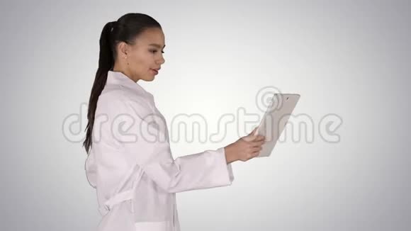 年轻的女医生手里拿着平板电脑在梯度背景下做视频呼叫视频的预览图