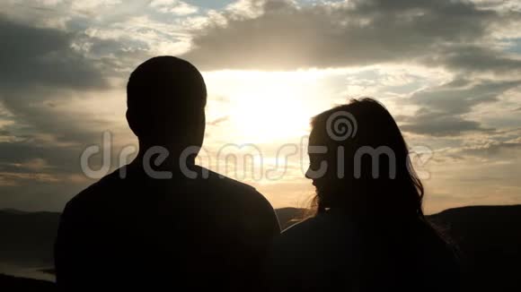 日落时分一对年轻夫妇的剪影一个女人把头放在男朋友肩膀上视频的预览图