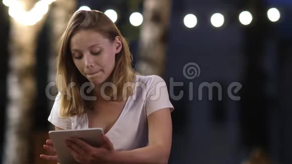 一个美丽的年轻女孩晚上在一台平板电脑上工作视频的预览图