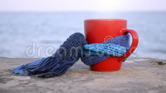 带热咖啡茶和蒸汽的红杯系着蓝色针织围巾视频的预览图