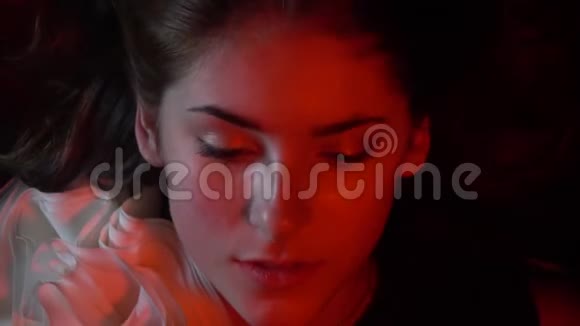在水下闭上一个红色灯光的女人的眼睛视频的预览图