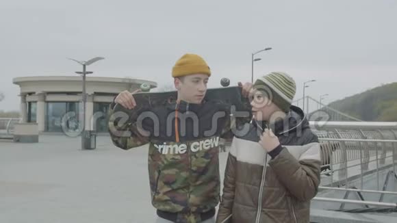 十几岁的男孩拿着溜冰鞋在城里聊天视频的预览图
