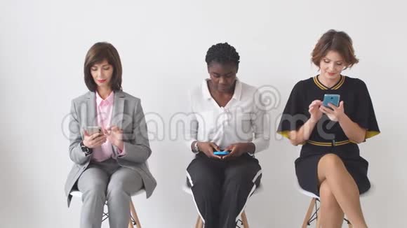 三位商务女士坐在椅子上等着面试一家大公司的高级职位视频的预览图