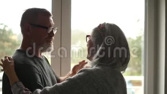 恋爱中的成熟夫妻情人节幸福而有爱心的老人在窗前跳舞视频的预览图