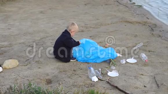 一个小男孩在公园里的河边或湖边的海滩上收集垃圾视频的预览图