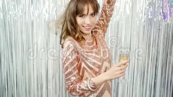 快乐的微笑嬉戏的美丽的年轻女子带着香槟酒杯庆祝新年嬉戏地看着视频的预览图