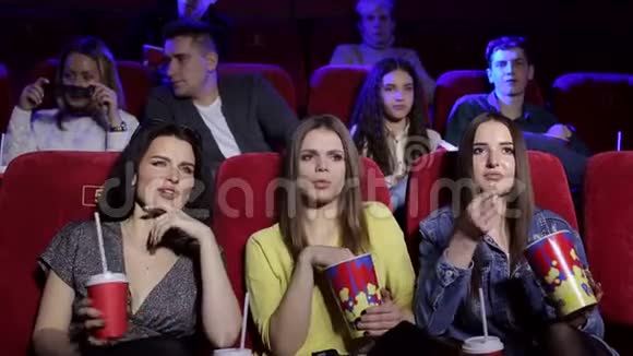 三个沮丧的年轻女孩在电影院看一部无趣的电影视频的预览图