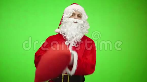圣诞老人带礼品袋色键绿色屏幕圣诞老人身后背着一袋红色的礼物被隔离在绿色上视频的预览图