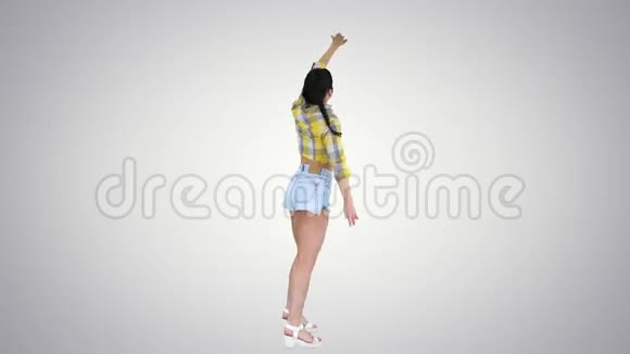 华丽可爱的女孩穿着牛仔裤短裤运动鞋在梯度背景下跳舞视频的预览图