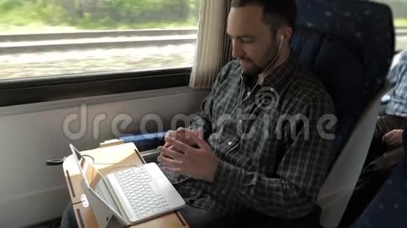 男人在火车上和他的笔记本电脑聊天视频的预览图
