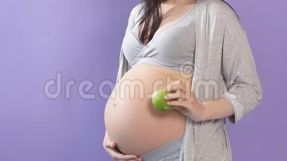 怀着大肚子抱着苹果的苗条孕妇被隔离在蓝墙上视频的预览图