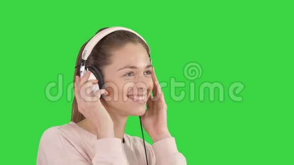 年轻漂亮的女人穿着鲜艳的衣服在绿色的屏幕上欣赏音乐铬钥匙视频的预览图