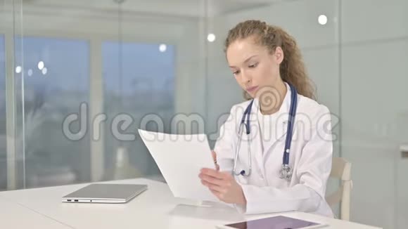 勤奋工作的年轻女性医生在办公室阅读文件视频的预览图