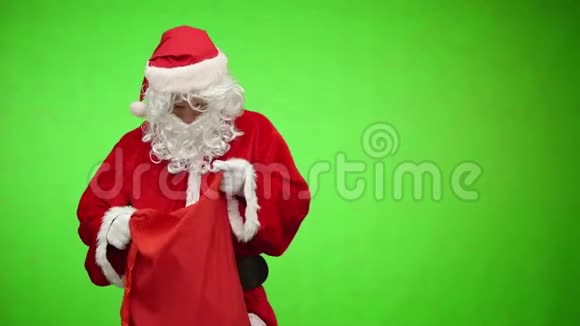 圣诞老人背着绿色的屏幕在包里拿礼物视频的预览图