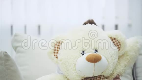 有趣的小女孩躲在白色的泰迪熊后面挥舞着它的爪子视频的预览图