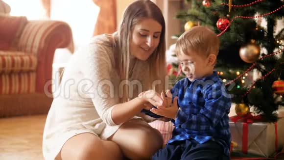 慢镜头视频快乐微笑的母亲和她的小儿子吹着闪闪发光的纸屑从手坐在下面视频的预览图