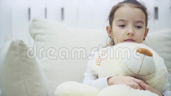 小迷人的女孩坐在沙发上拥抱着她的大毛绒朋友叹了口气她似乎很沮丧和担心视频的预览图