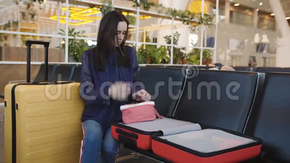 女人拿着一个打开的手提箱坐在机场把它放在他的钱包里视频的预览图