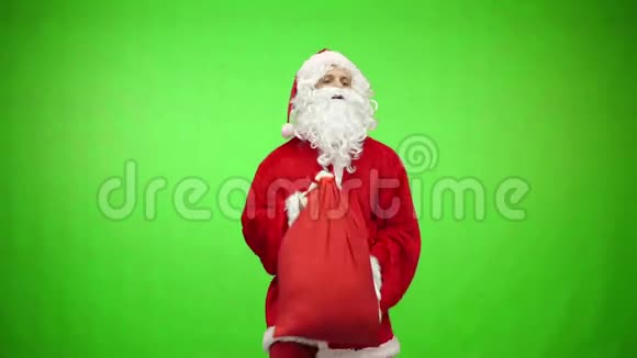侧面看圣诞老人背着礼物在袋子绿色背景铬钥匙4k镜头视频的预览图