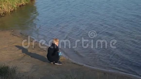 一个小男孩帮助收集海滩上的垃圾和河里的水视频的预览图