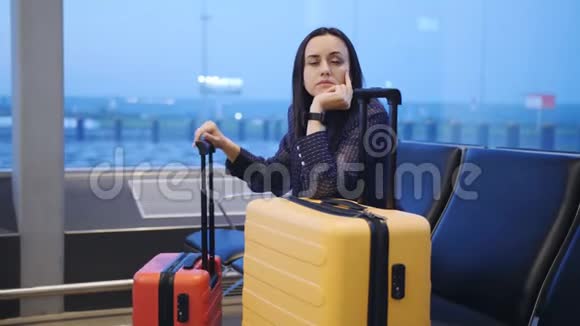 黎明时分一个无聊的女人带着旅行箱在机场休息室等待航班上的移植视频的预览图