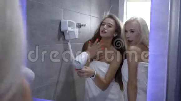 淋浴的乐趣年轻和迷人的女性进入毛巾享受浴室的乐趣有趣的玩吹风机唱歌视频的预览图