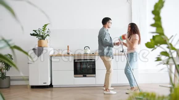 女孩和男人在厨房里和拖把和清洁工跳舞视频的预览图