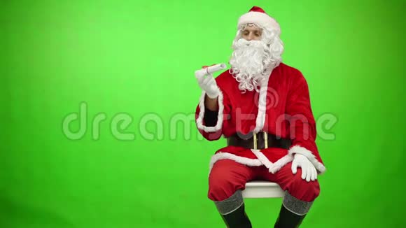 圣诞老人读字母色度键绿色屏幕圣诞老人从怀里掏出一张纸孤立地贴在上面视频的预览图