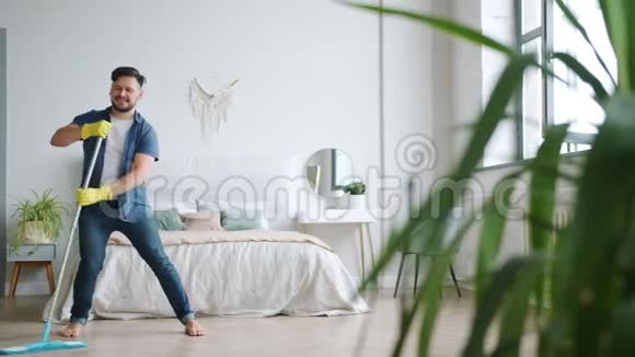 疯狂的人在家玩独自在拖把跳舞在洗衣服的地板上唱歌视频的预览图