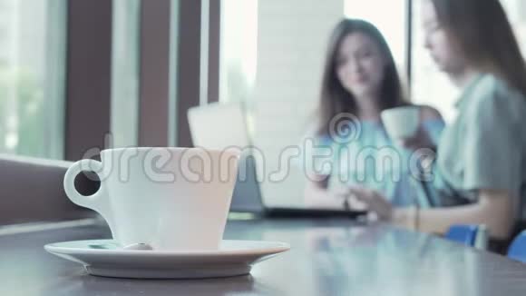 一杯咖啡放在两个学生桌上他们正在做一个背景项目视频的预览图
