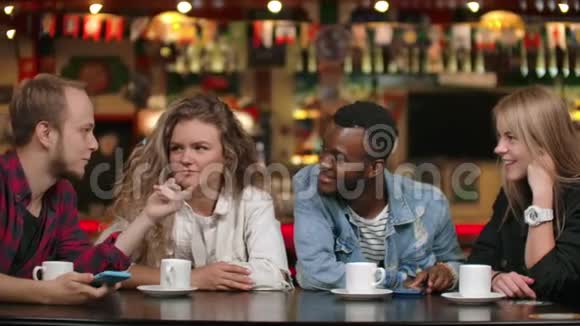 跨国集团的男人和女人坐在一张端着咖啡的桌子旁笑着说着视频的预览图