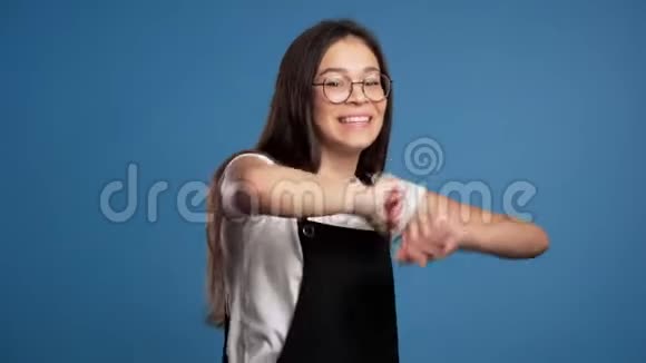 漂亮的戴眼镜的亚洲女孩在蓝色背景下微笑和跳舞心情很好幸福党性观念视频的预览图