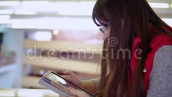 年轻的黑发女人用平板电脑上网视频的预览图
