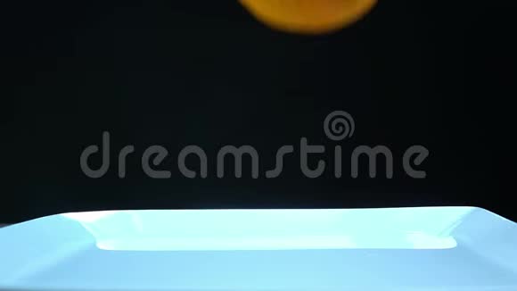 橘子在黑色的背景下慢慢掉进水里视频的预览图
