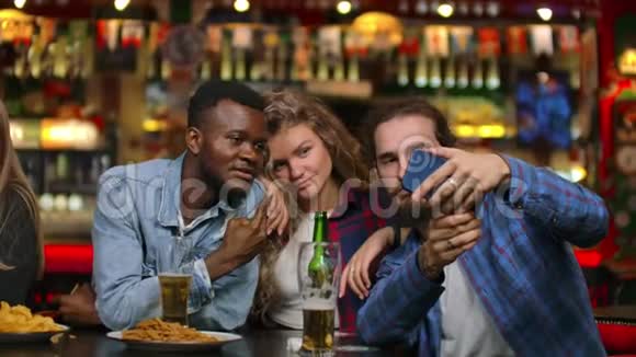 三个朋友两个欧洲人和非裔美国人坐在啤酒酒吧时被拍在一起视频的预览图