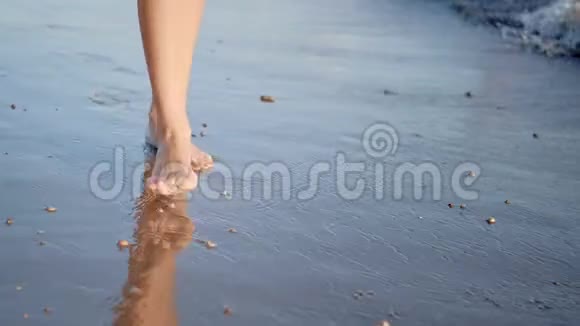 赤脚旅行阳光明媚的女孩在沙滩上散步平静的海浪享受暑假视频的预览图