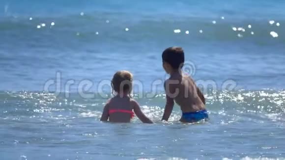 小男孩和小女孩在海浪上跳跃视频的预览图