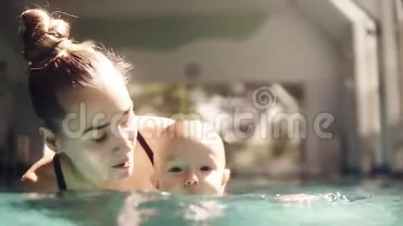 宝贝和他妈妈上了第一节游泳课健康的母亲教孩子在游泳池游泳视频的预览图