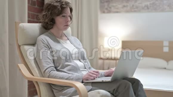 在沙发上用笔记本电脑聊天的老女人视频的预览图