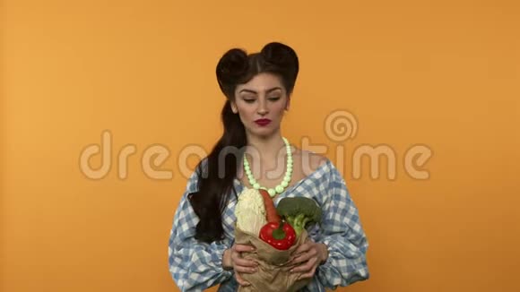 在黄色背景下购物后女人手里拿着带蔬菜的纸袋视频的预览图