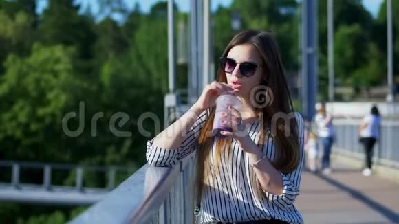 美丽的女游客在桥上喝一杯冷鸡尾酒视频的预览图