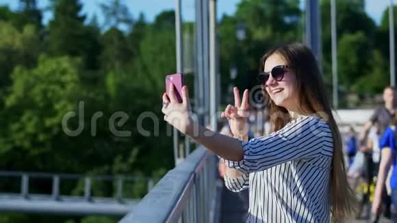 年轻的女商人在桥上度假时为社交网络自拍视频的预览图