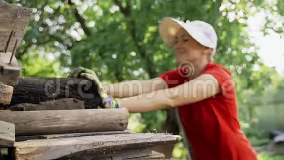 一个穿着红色t恤的女人在花园里整齐地储存着运输手推车上的木柴为冬季取暖和视频的预览图