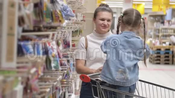 微笑的母亲和孩子坐在超市的手推车里女儿帮助母亲选择空气气球视频的预览图