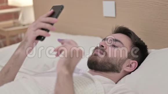 在床上使用智能手机的帅哥视频的预览图