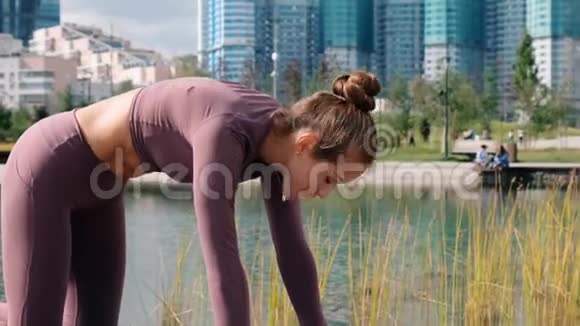 年轻女子在城市背景下做瑜伽牛和猫操视频的预览图