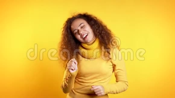 年轻可爱的女孩在黄色的工作室背景下跳舞女人穿着鲜艳的衣服视频的预览图