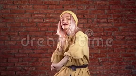 不寻常的女人粉红色的头发微笑着在砖背景的工作室里跳舞视频的预览图